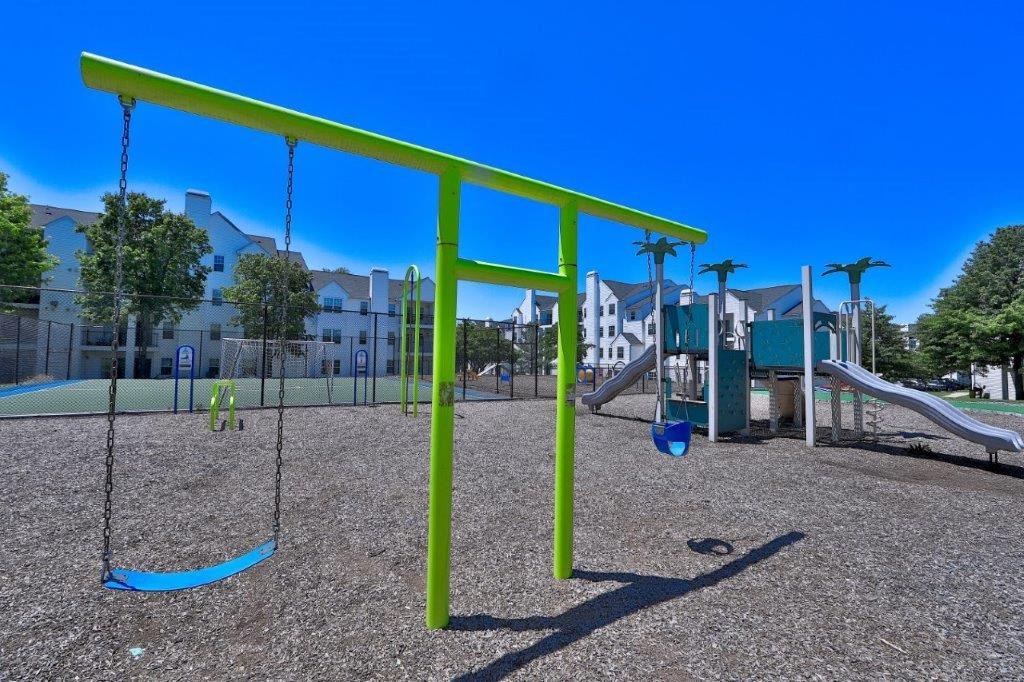 a playground with swings and a building in the background