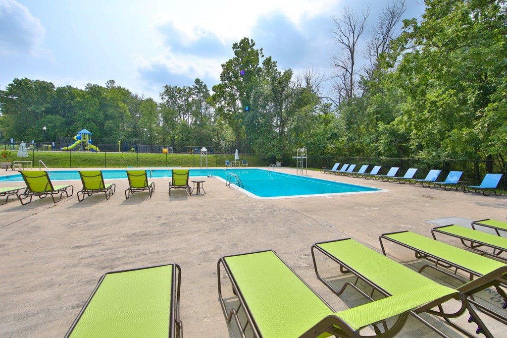 a swimming pool with green chairs around it
