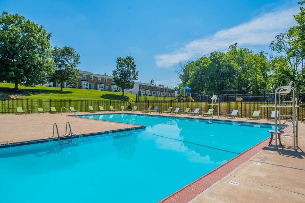 a swimming pool with trees and a building in the background