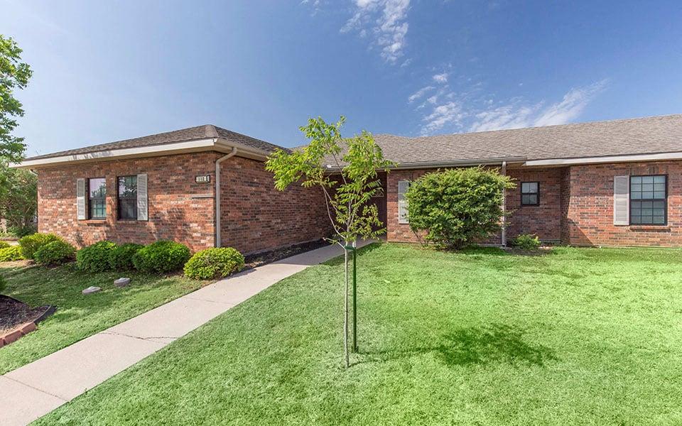 a brick house with a yard and a sidewalk