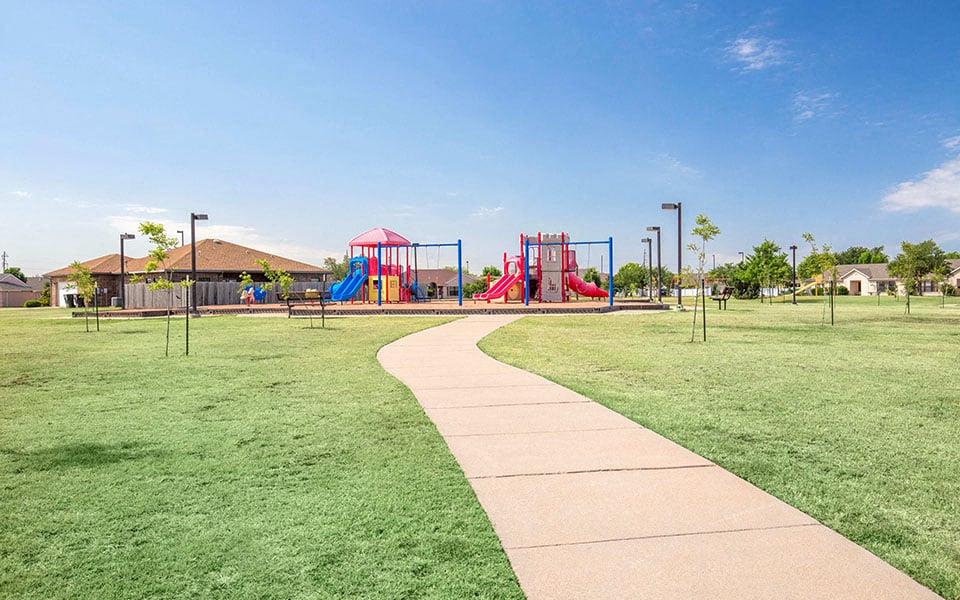 a sidewalk leading to a childrens play park