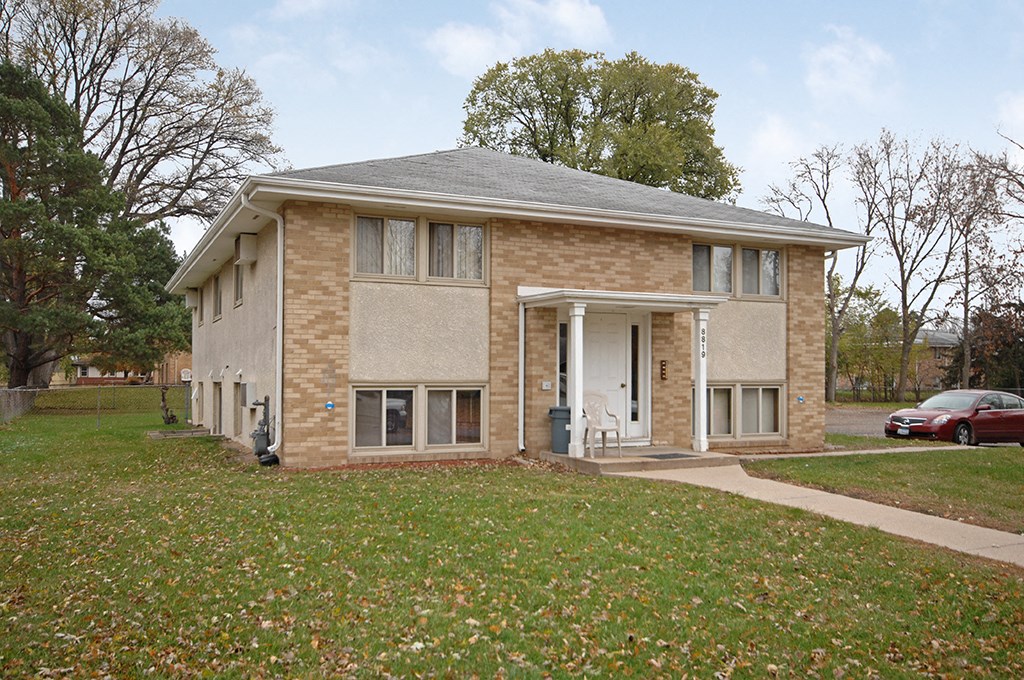 a small brick house with a lawn in front of it