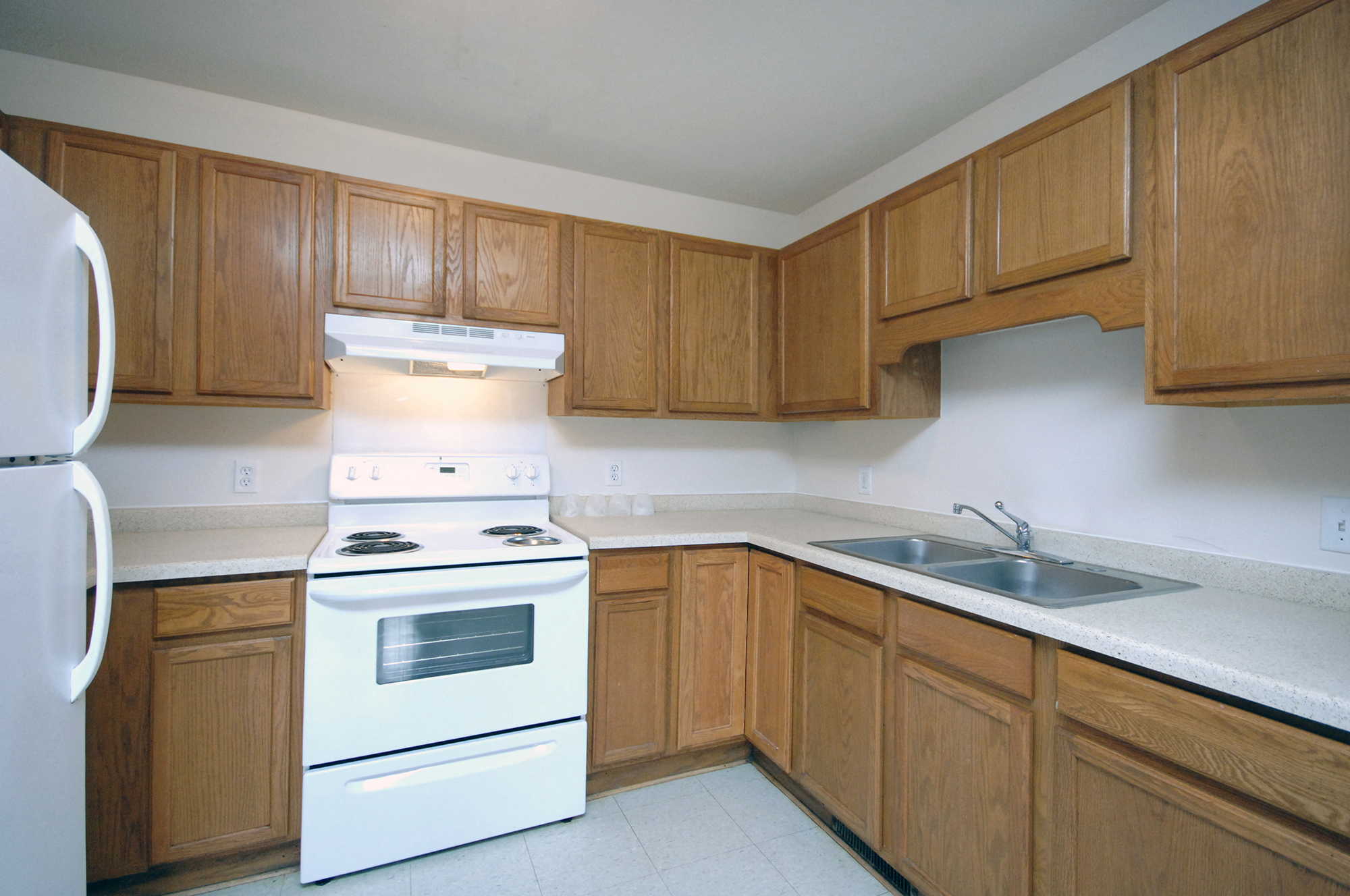 an empty kitchen with wooden cabinets and white appliances