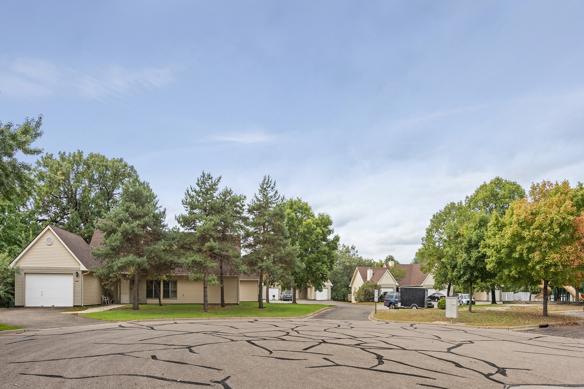 an empty parking lot in a neighborhood with houses and trees