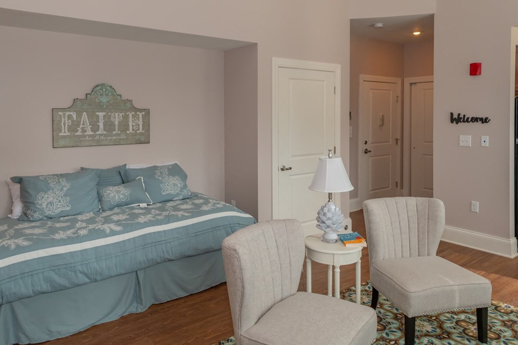a bedroom with a bed and two chairs and a table