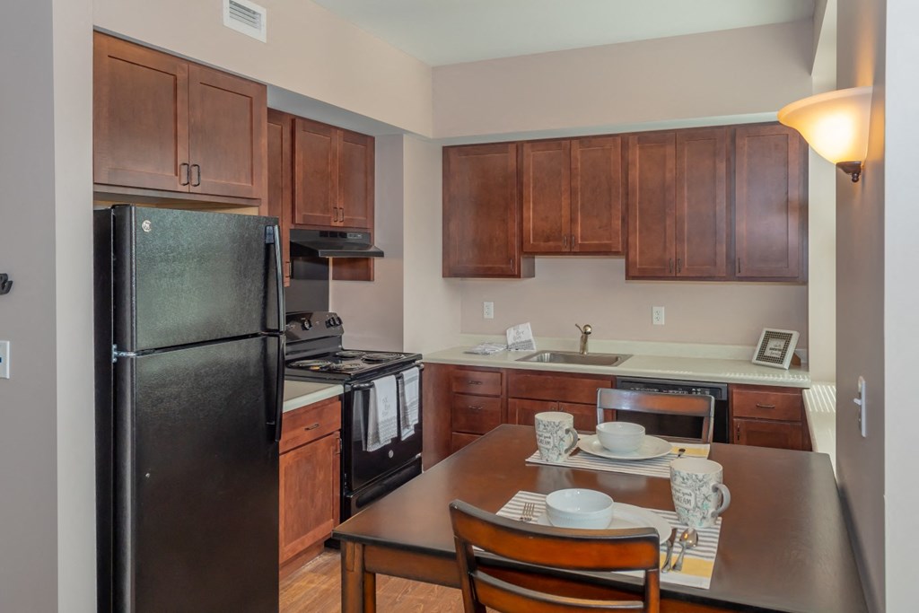 a kitchen with black appliances and a wooden table and chairs