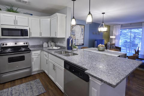 A kitchen with white cabinets and a granite countertop.