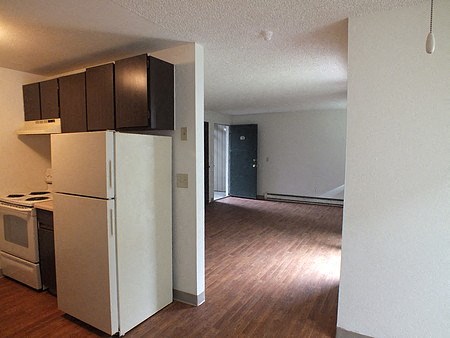 an empty kitchen with a white refrigerator and cabinets
