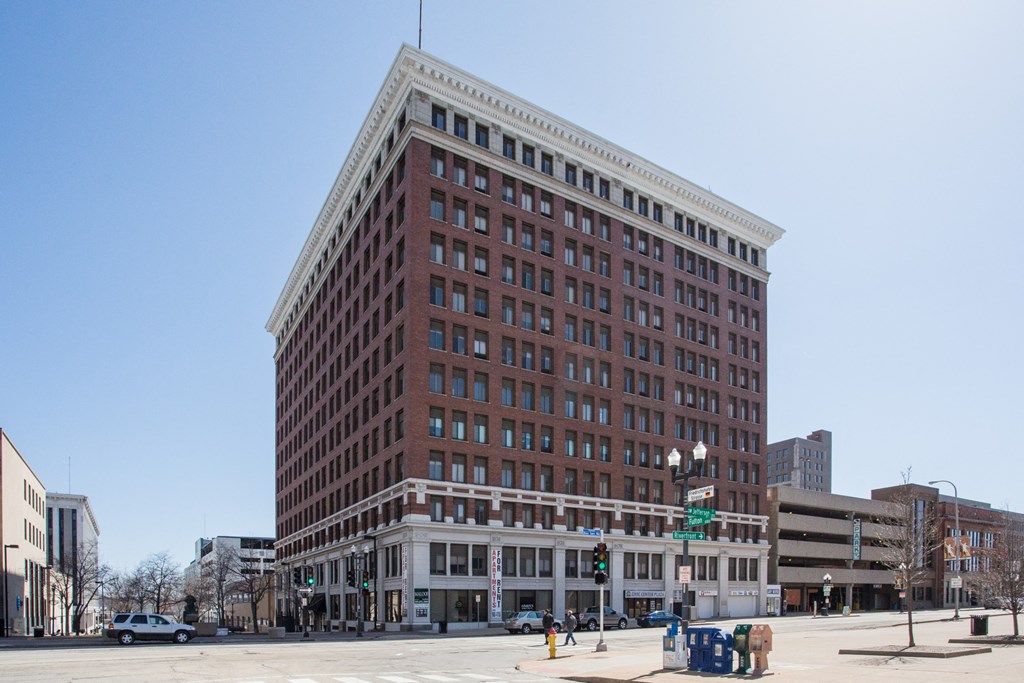 a tall red brick building with many windows on a city street
