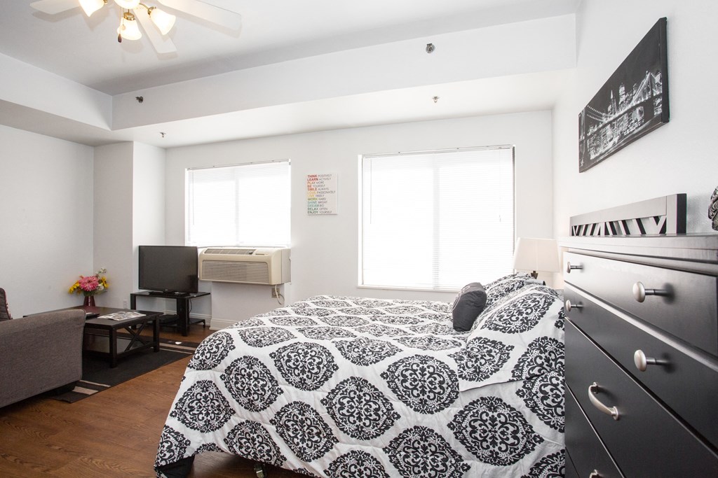 a bedroom with a bed and a dresser and a tv