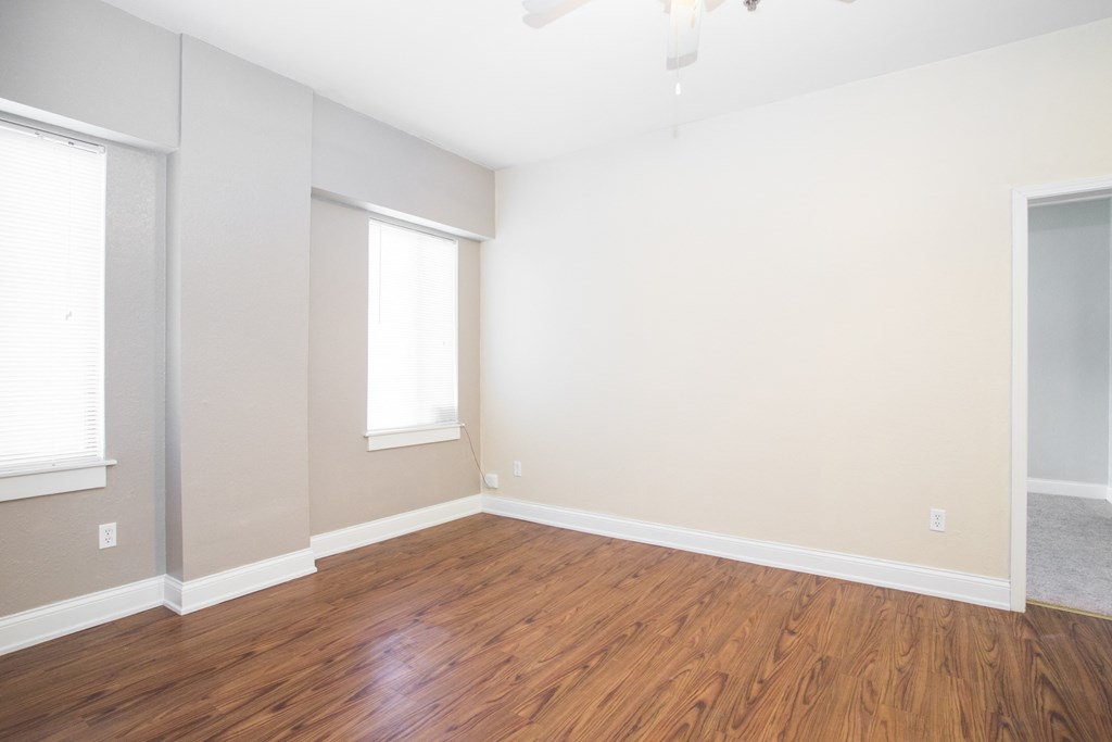 an empty living room with wood floors and white walls