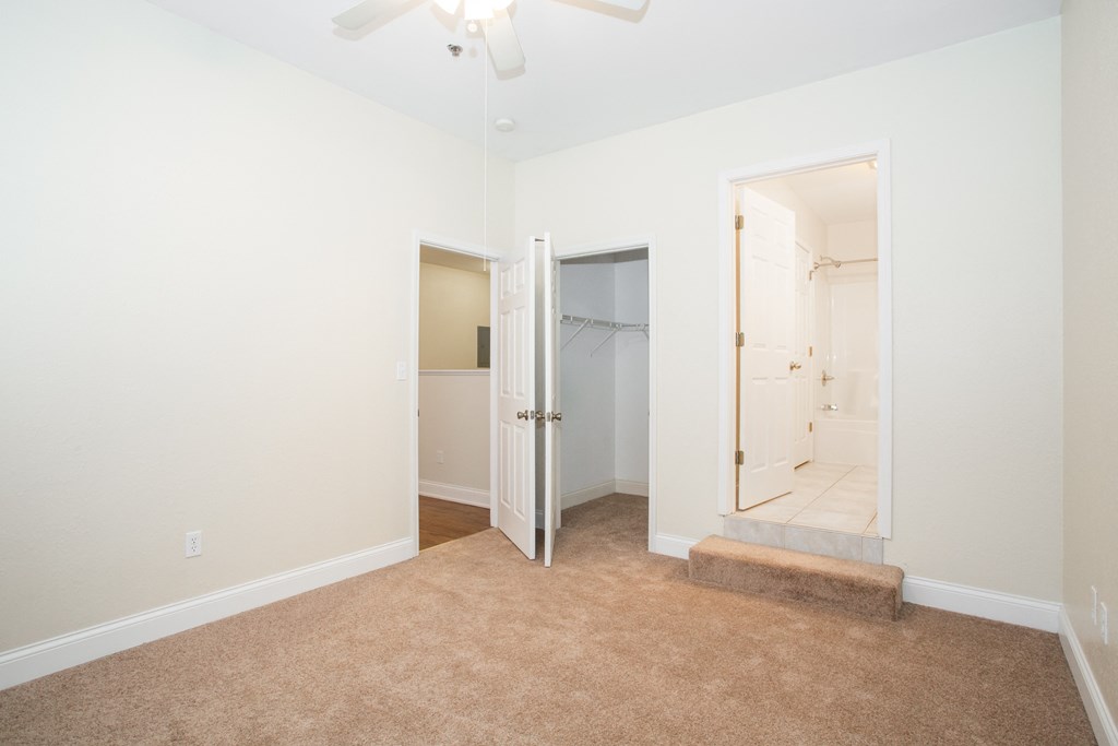 a bedroom with a door to a closet and a bathroom