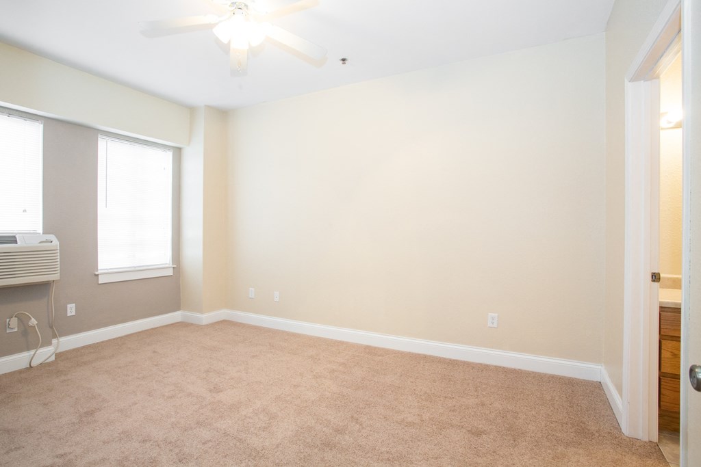 an empty living room with a ceiling fan and a window