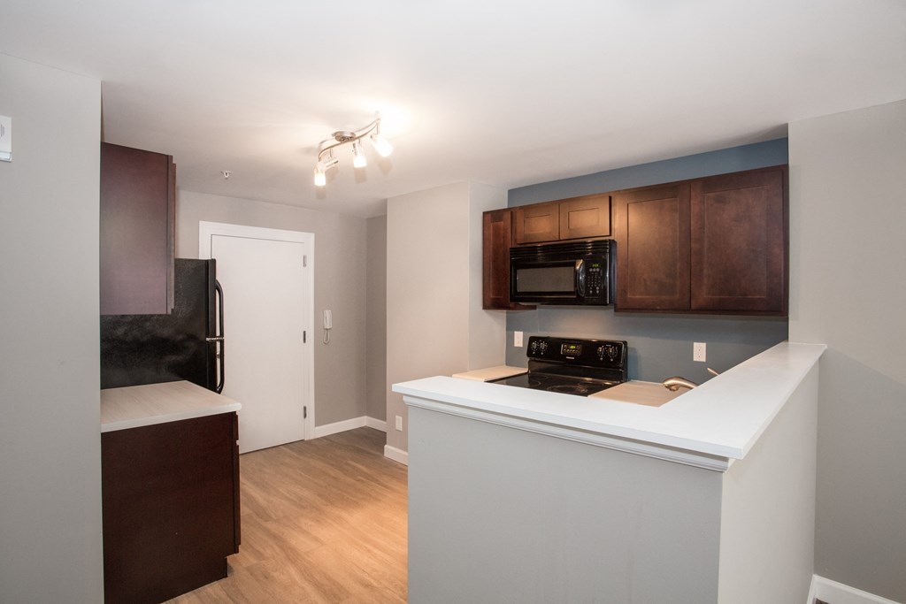 a kitchen with a white counter top and a stove and a microwave