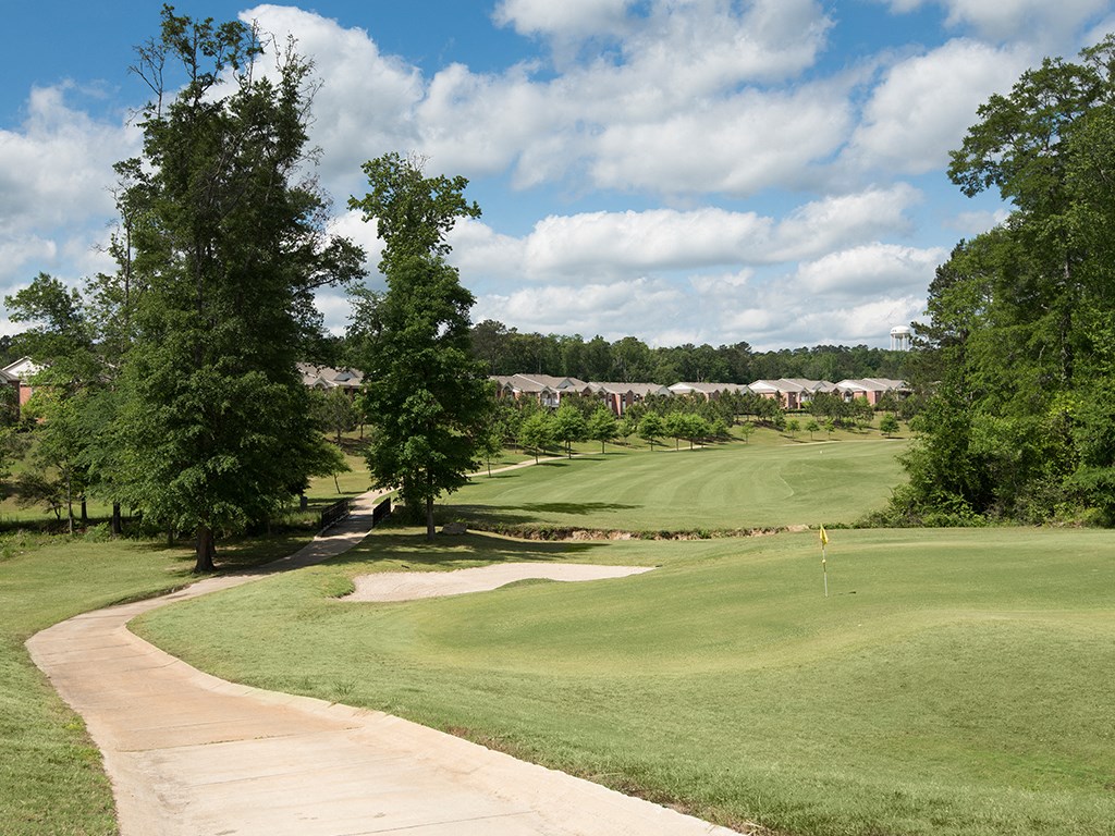 a view of a golf course with trees and houses in the background