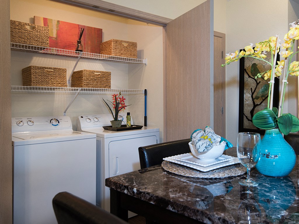a kitchen with a washer and dryer and a table with a vase