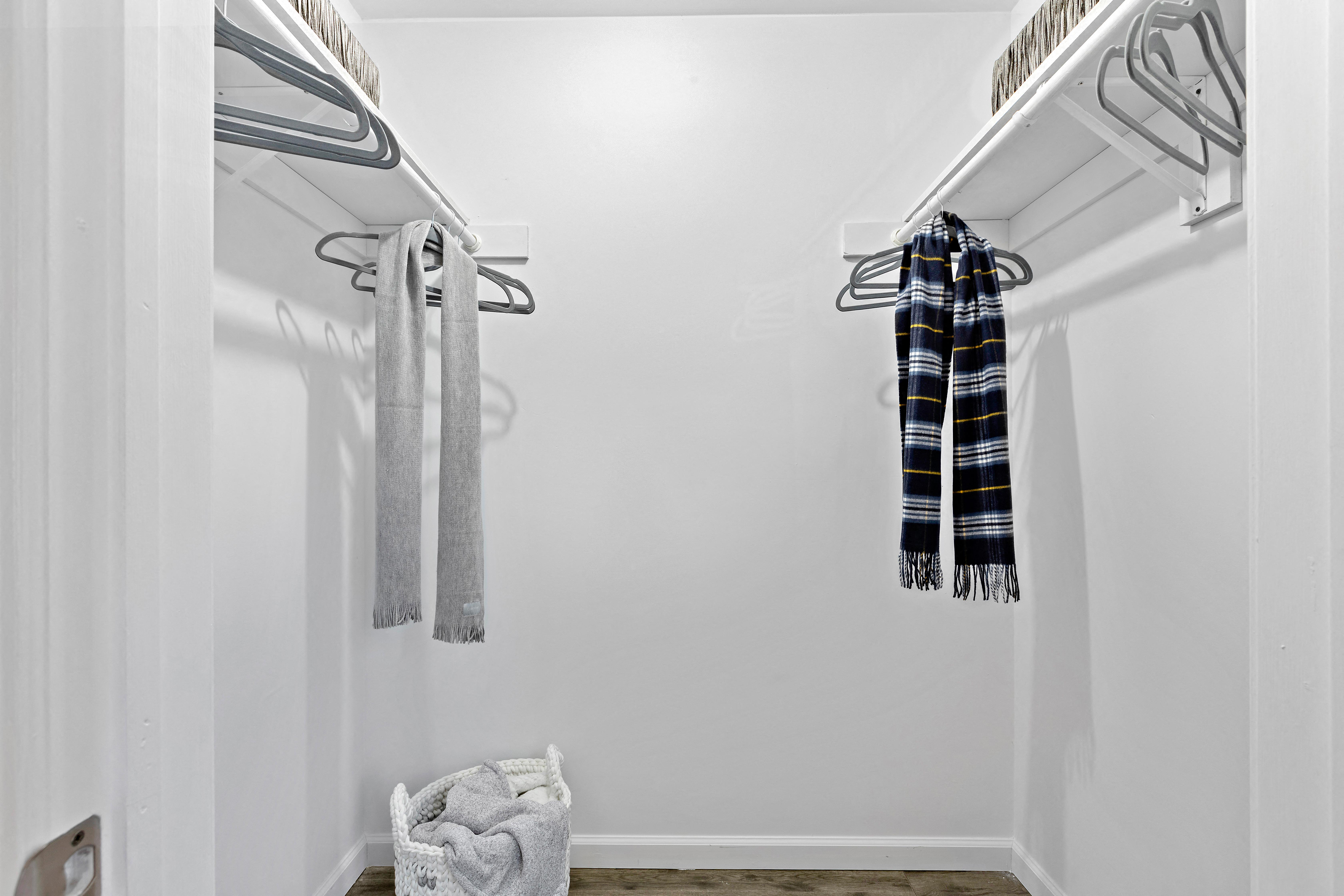 his and hers closets with towels and hangers in a small white room