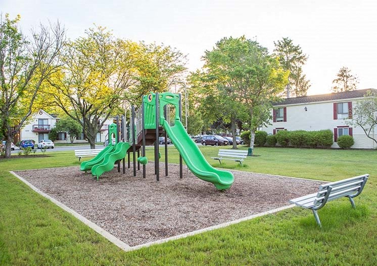 a playground with slides and benches in a park