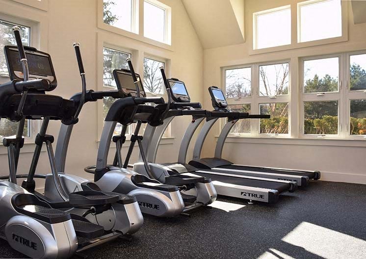 a row of exercise bikes in a room with windows
