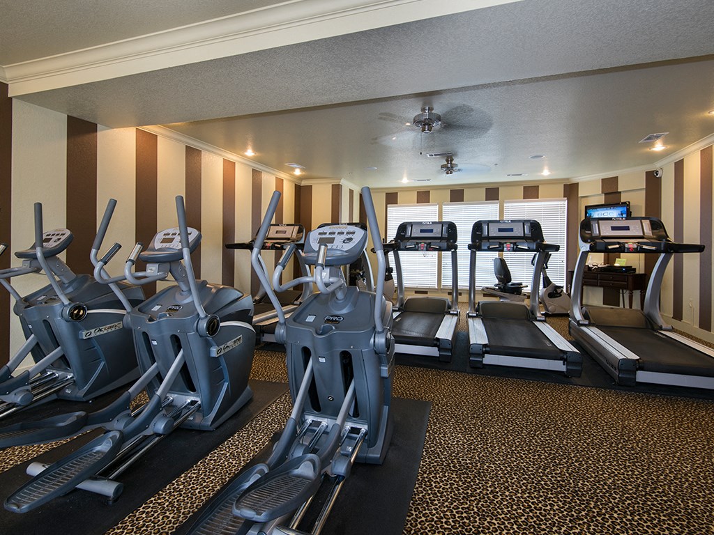 a gym with cardio machines and a ceiling fan