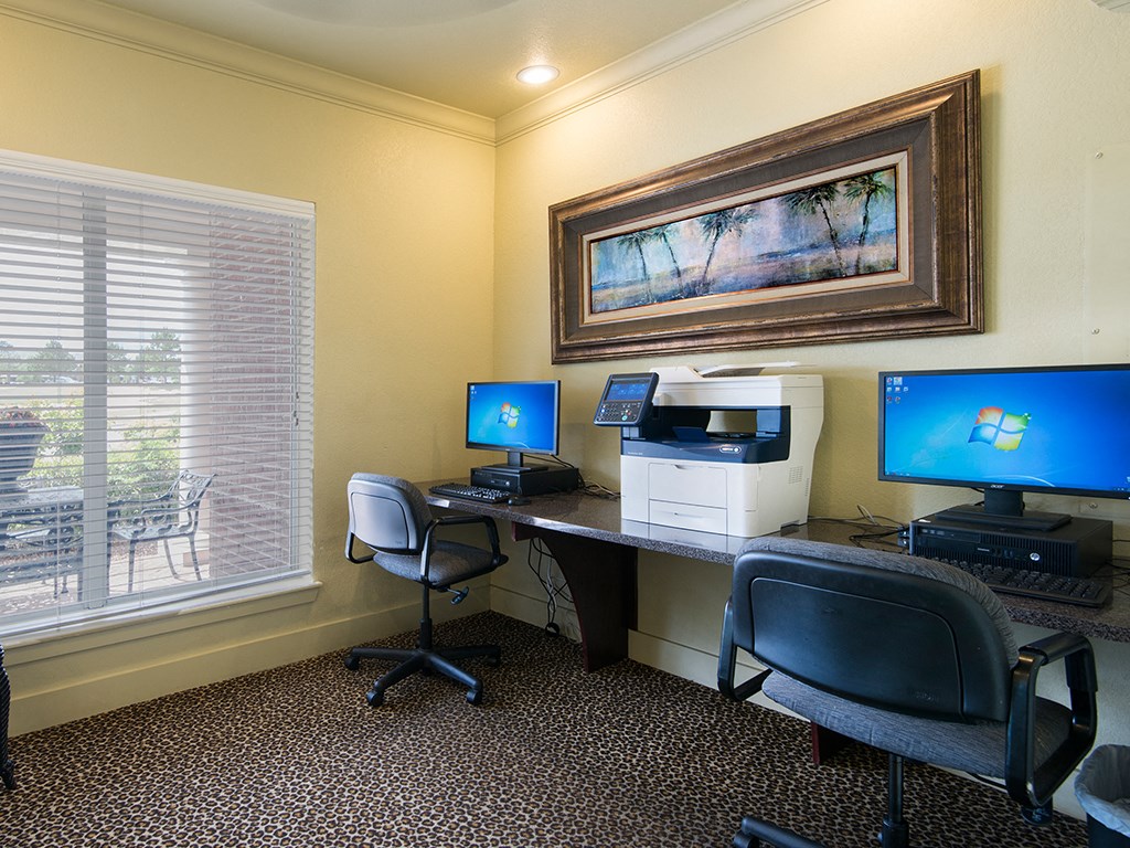 a home office with two computers and a printer on a desk