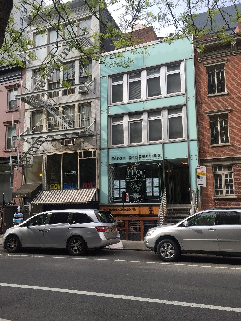 a city street with cars parked in front of a blue building