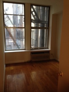 an empty living room with large windows and wooden floors