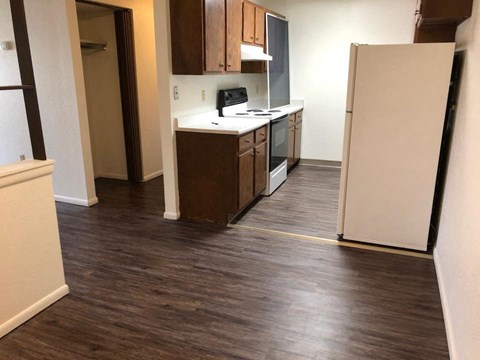 an empty kitchen with wood floors and a refrigerator