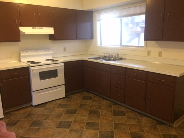 a kitchen with a stove and a sink and a window