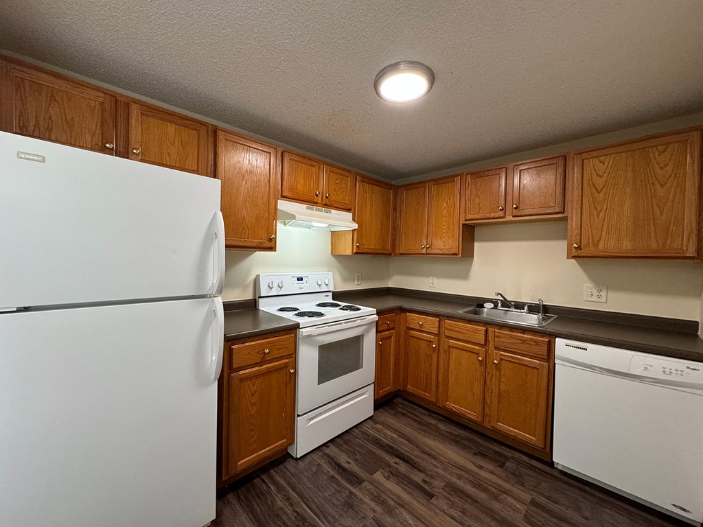 A kitchen with white appliances and wooden cabinets.