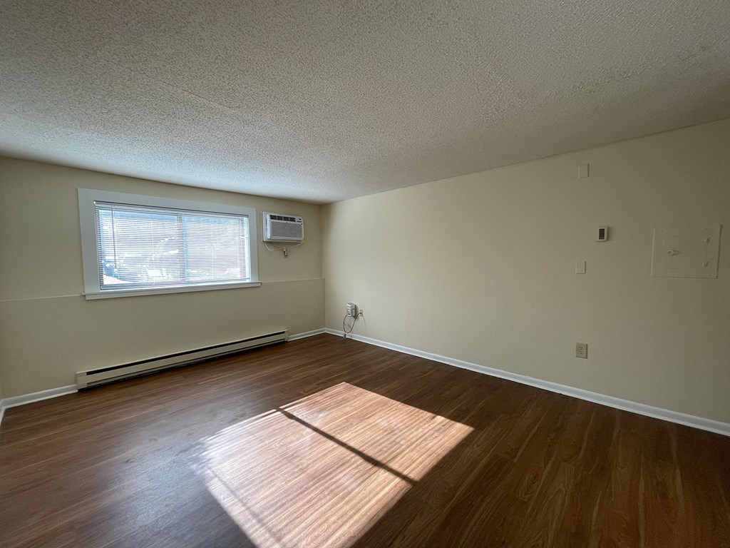 A room with a window and a wooden floor.