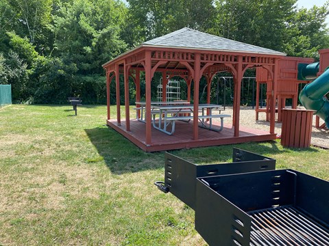 A gazebo is surrounded by a green lawn.