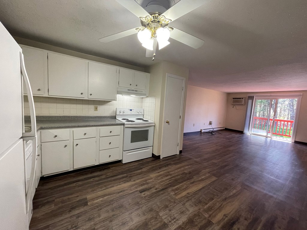 A kitchen with white appliances and wooden floors.