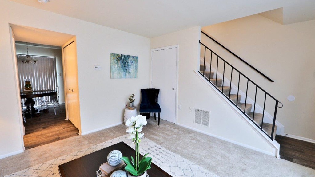 a living room with a staircase and a dining room
