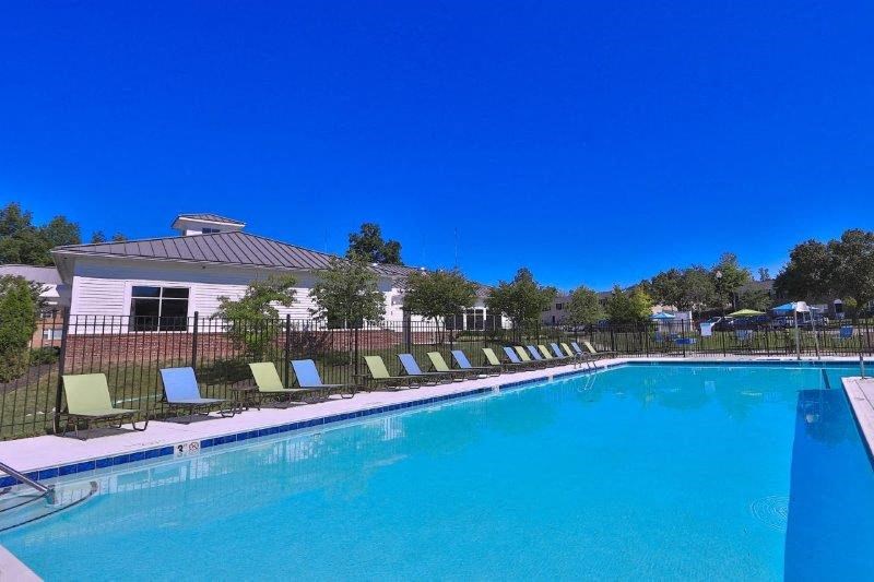 a large swimming pool with chairs in front of a house