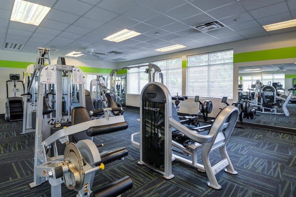 a gym with weights and cardio equipment in a building with windows