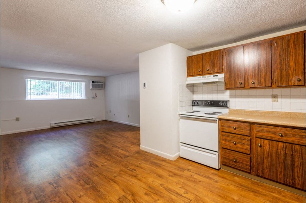 an empty kitchen with wooden floors and white appliances