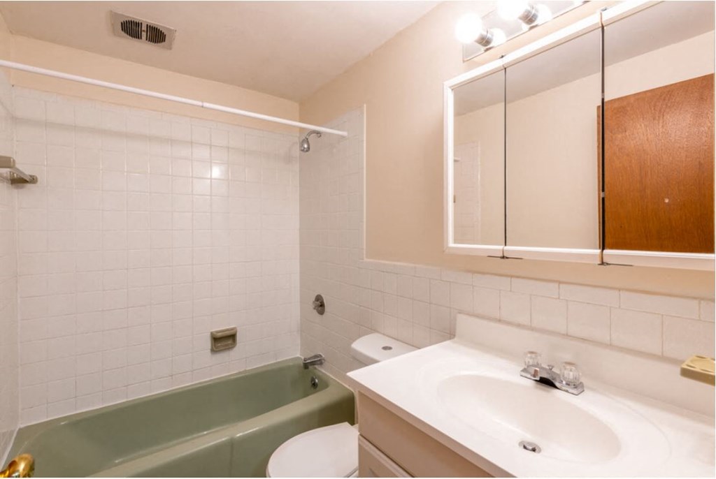 a white bathroom with a green bath tub and a sink