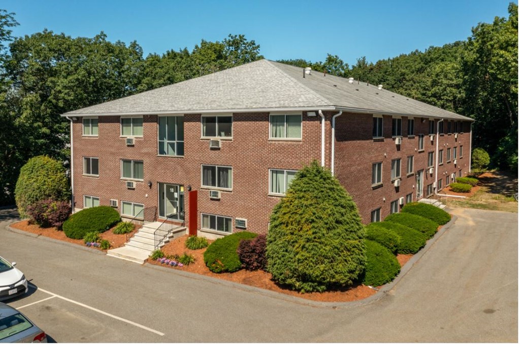 an aerial view of a brick apartment building with a parking lot