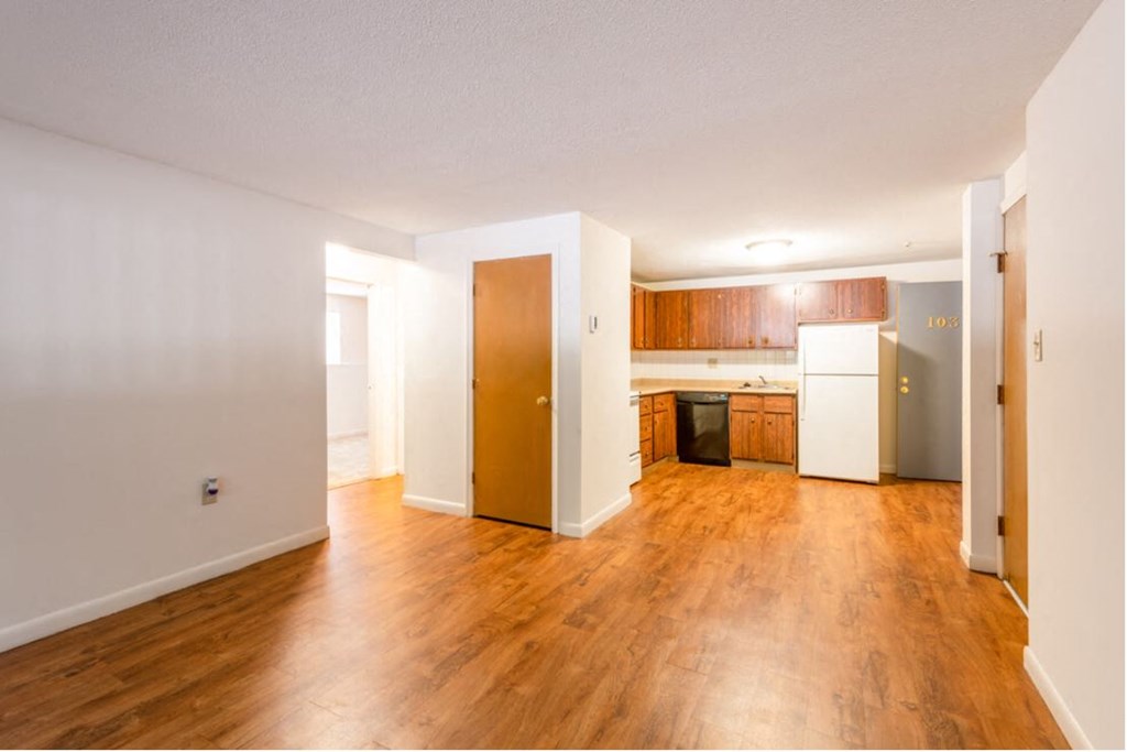 an empty living room and kitchen with wood floors