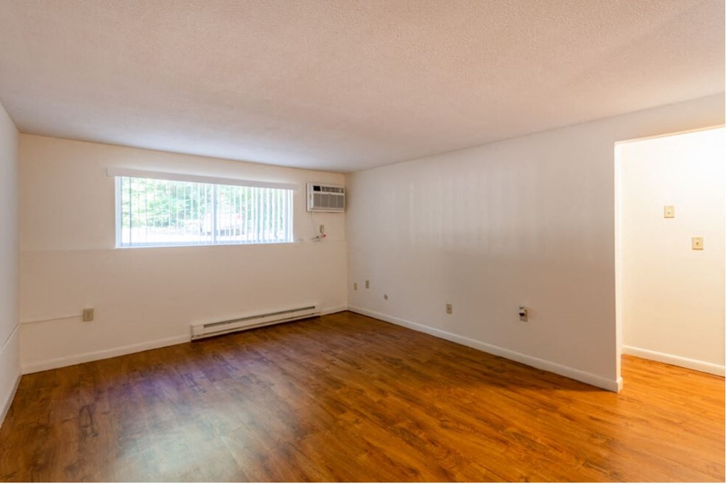an empty living room with wood floors and a window