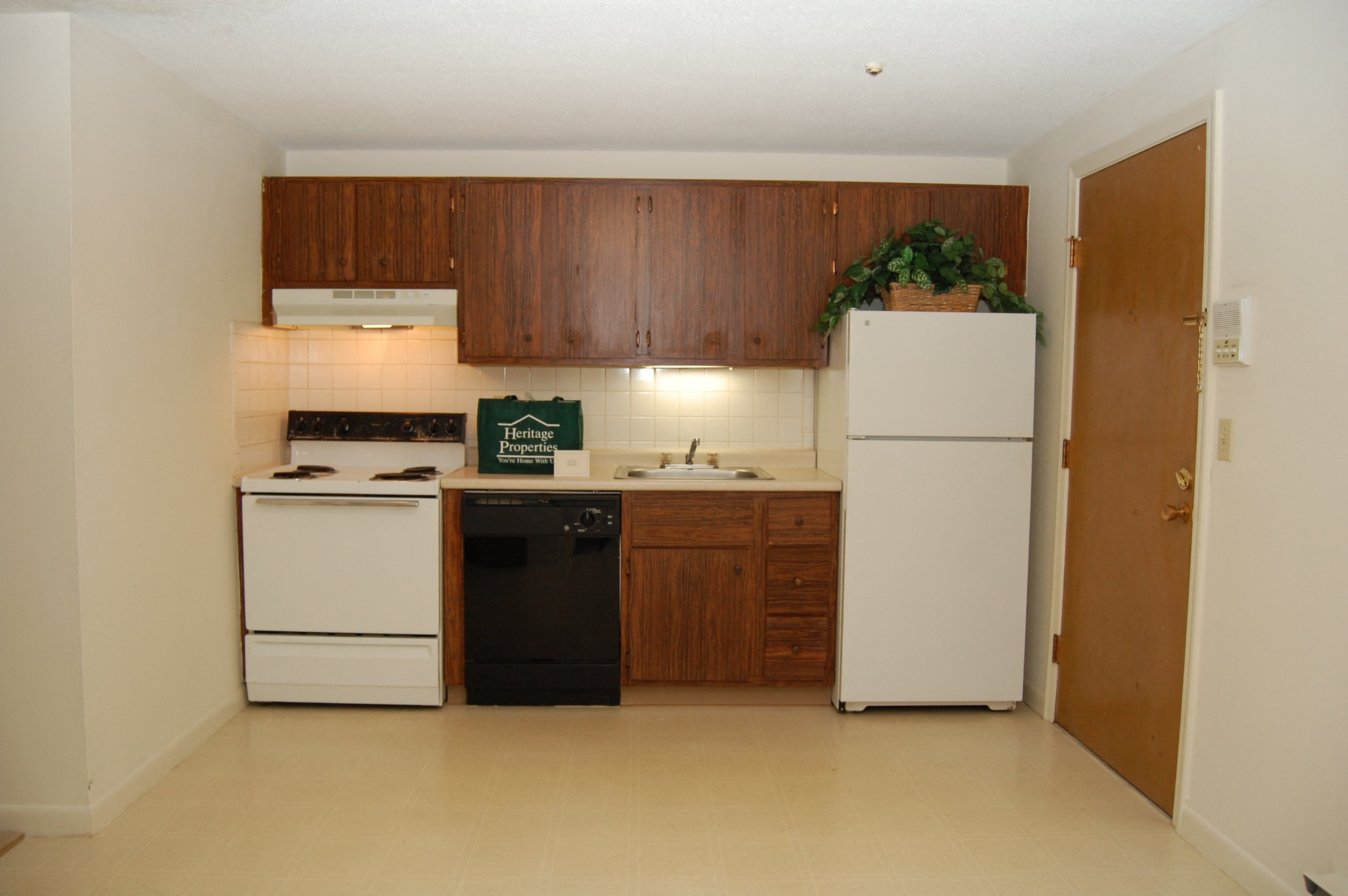 an empty kitchen with white appliances and wooden cabinets
