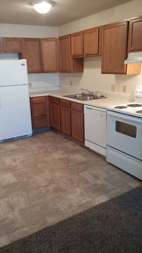 an empty kitchen with white appliances and wooden cabinets