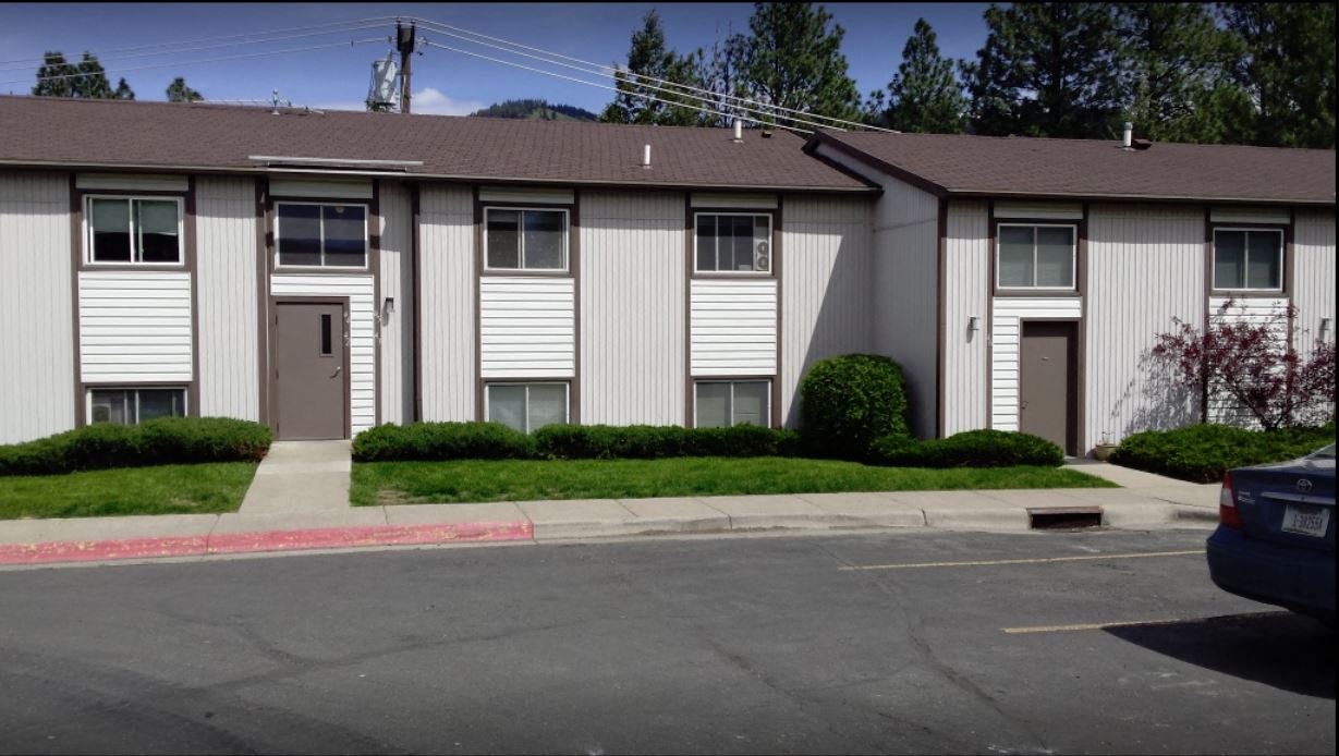 an apartment building with white siding and a street in front of it