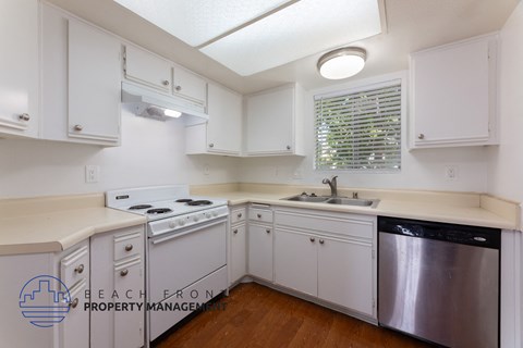 a kitchen with white cabinets and white appliances and a sink