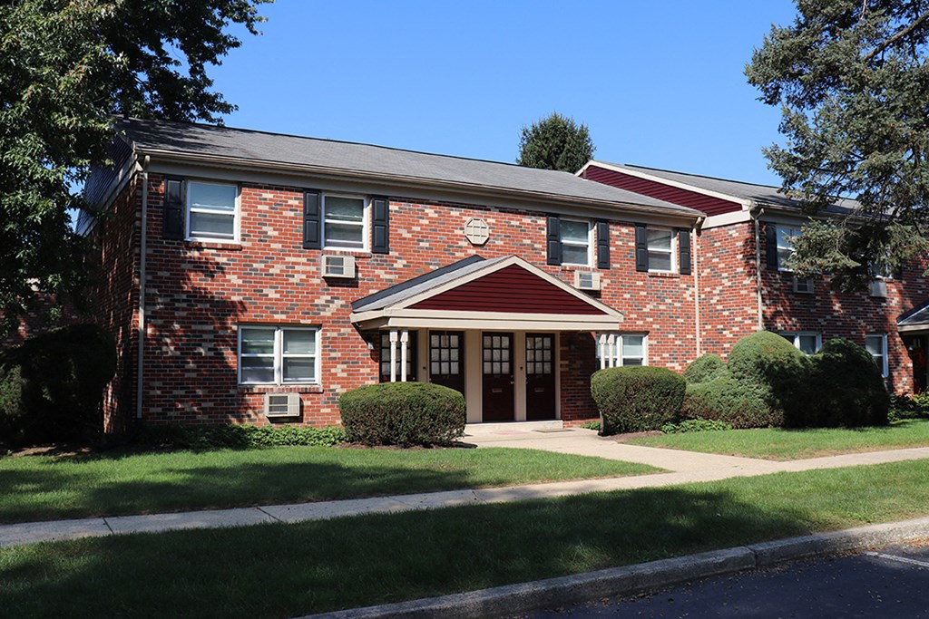 a red brick house with a sidewalk in front of it
