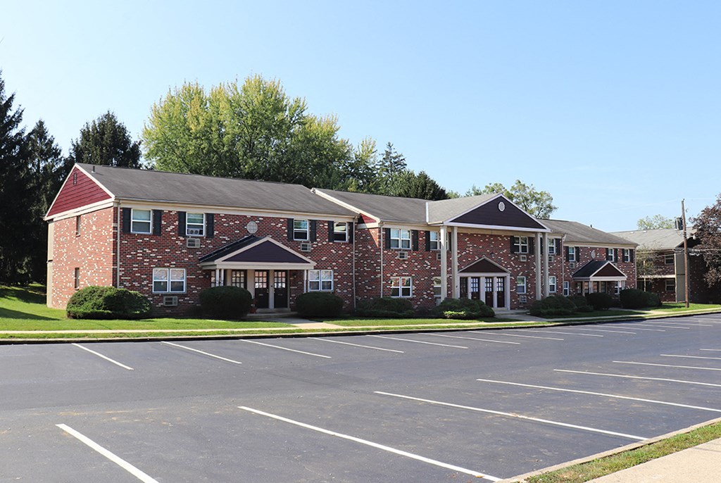 an empty parking lot in front of a brick apartment building