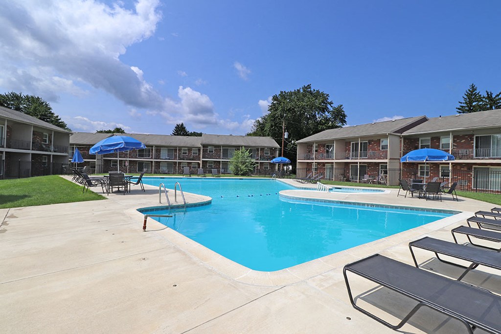 a resort style swimming pool with umbrellas in front of a building