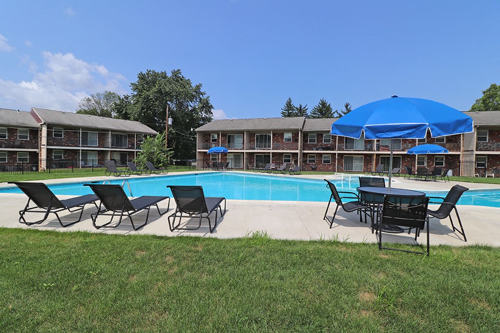 a pool with chairs and umbrellas in front of a building