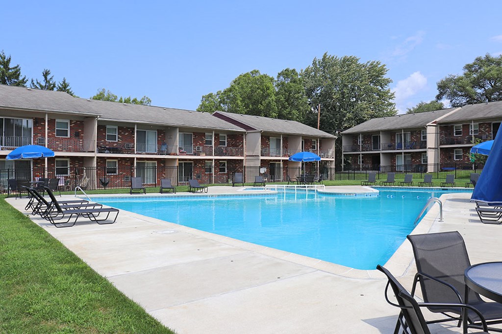 a swimming pool with chairs and umbrellas in front of a resort style pool